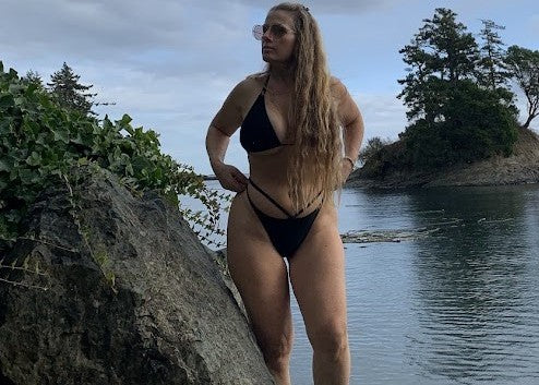 woman with black bikini on a rocky beach - jasikini swimwear