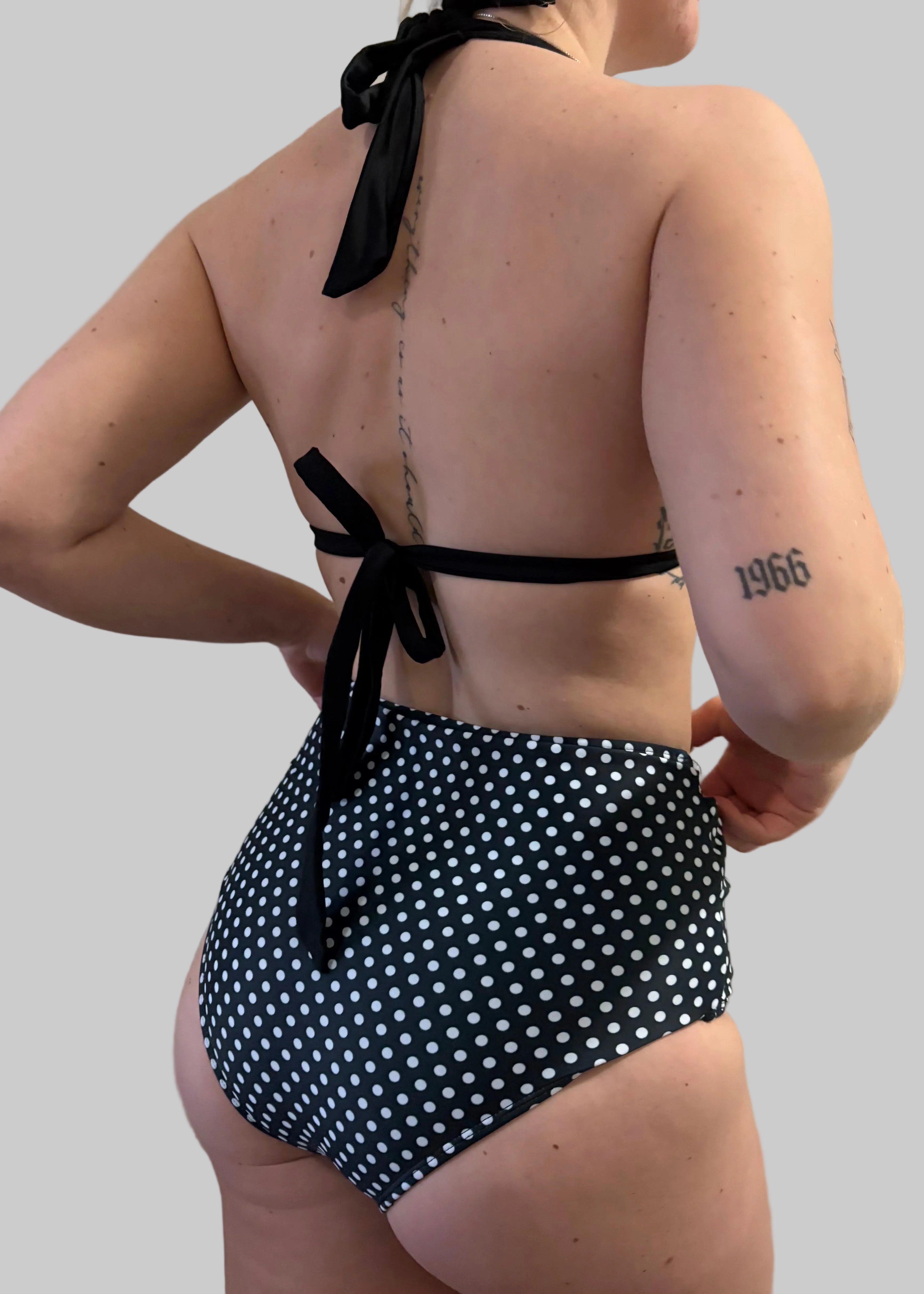 Back view of a woman wearing a black and white full coverage polka dot bikini - Jasikini swimwear.