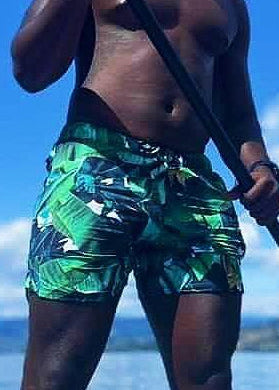 man on a paddleboard with palm leave designed swim shorts - Jasikini swimwear
