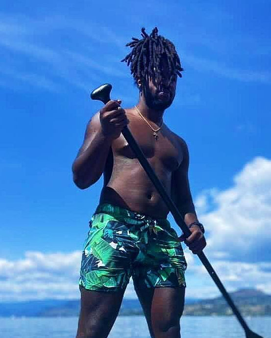 man on a paddleboard with palm leave designed swim shorts